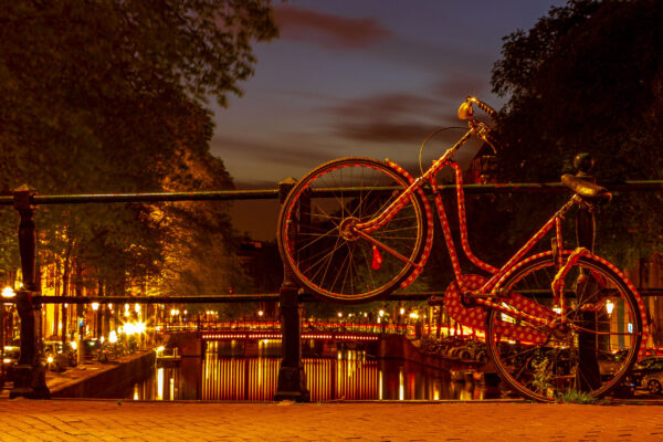 Iconic bicycle in Amsterdam, Netherlands, parked by a canal with traditional Dutch houses in the background