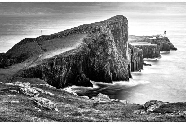 Neist Point Lighthouse on the Isle of Skye, Scotland, perched on dramatic sea cliffs at sunset