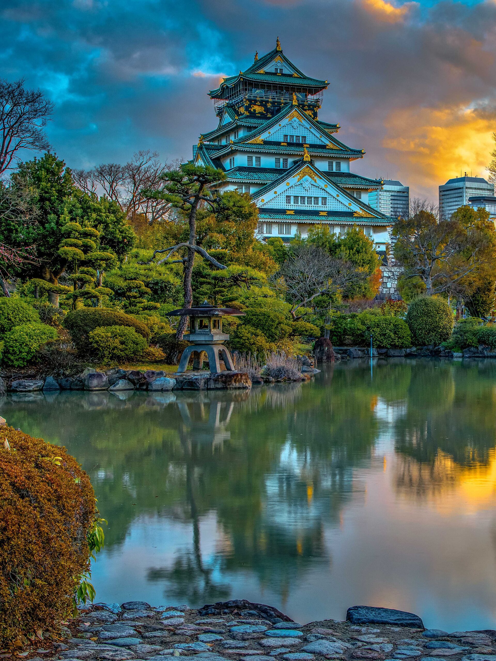 Sunrise over Osaka Castle in Japan with its reflection in a nearby lake
