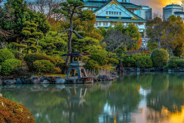 Sunrise over Osaka Castle in Japan with its reflection in a nearby lake