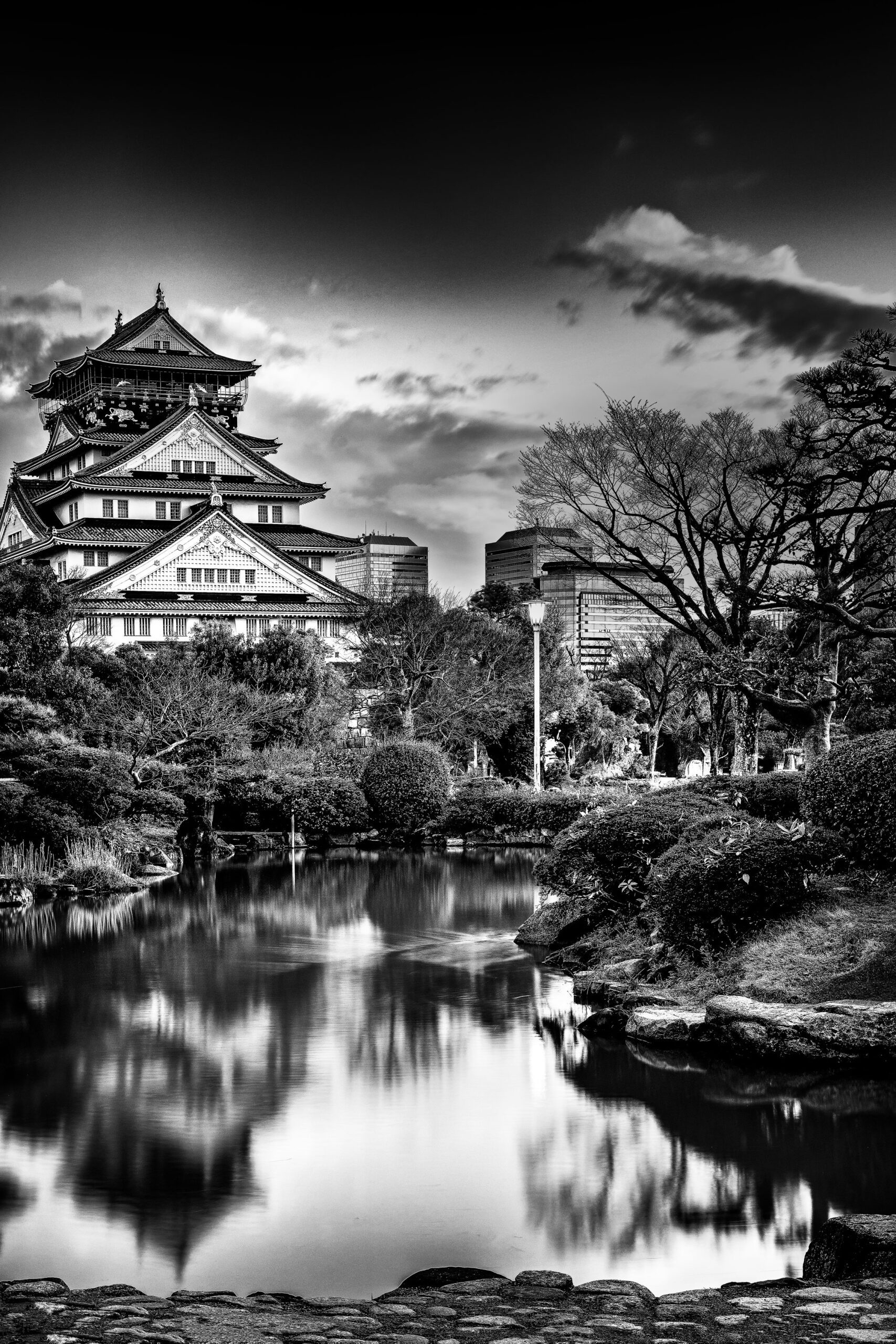 Black and white photograph of Osaka Castle in Japan with its reflection in the surrounding moat