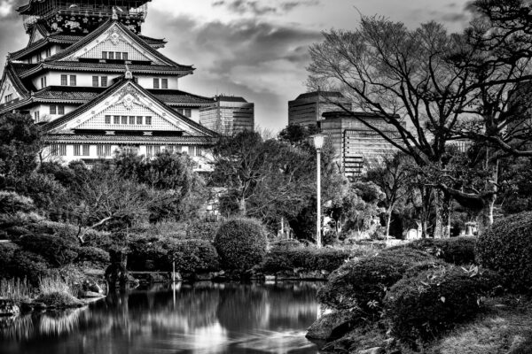Black and white photograph of Osaka Castle in Japan with its reflection in the surrounding moat