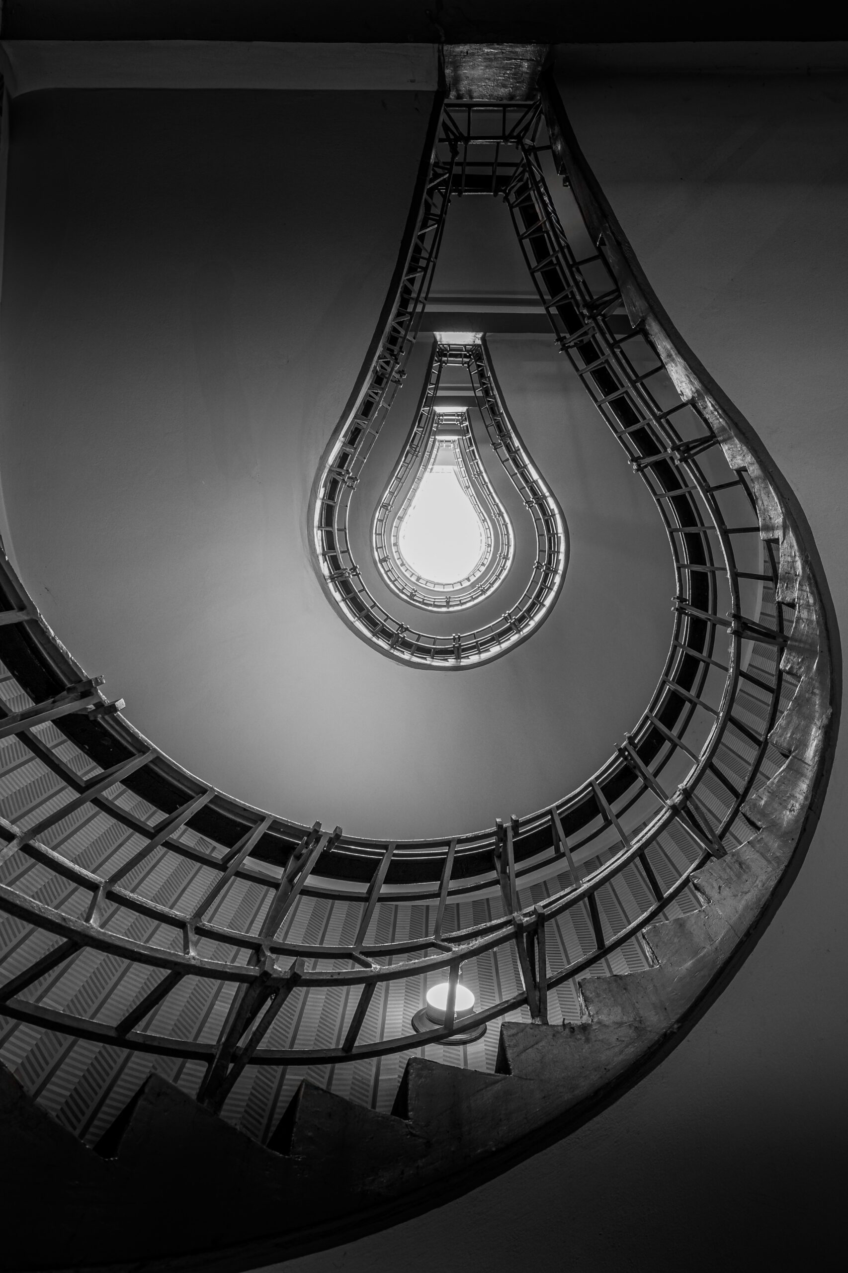 Bulb-shaped spiral staircase in Prague viewed from below, resembling a glowing light bulb