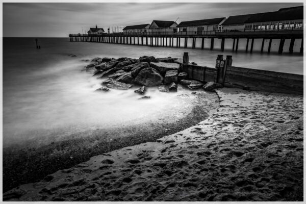 Southwold Pier in Suffolk, England, stretching into the North Sea with colourful beach huts nearby